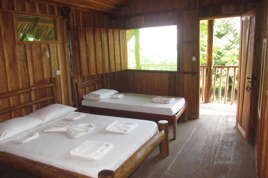 Lodge bedroom interior with private balcony and forest views